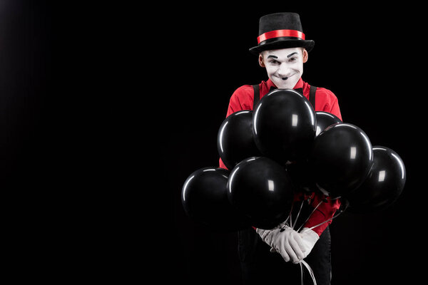 grimacing mime with bundle of helium balloons isolated on black