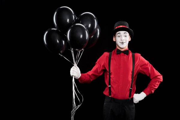 mime holding bundle of black balloons isolated on black