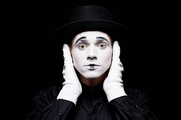 mime covering ears and looking at camera isolated on black