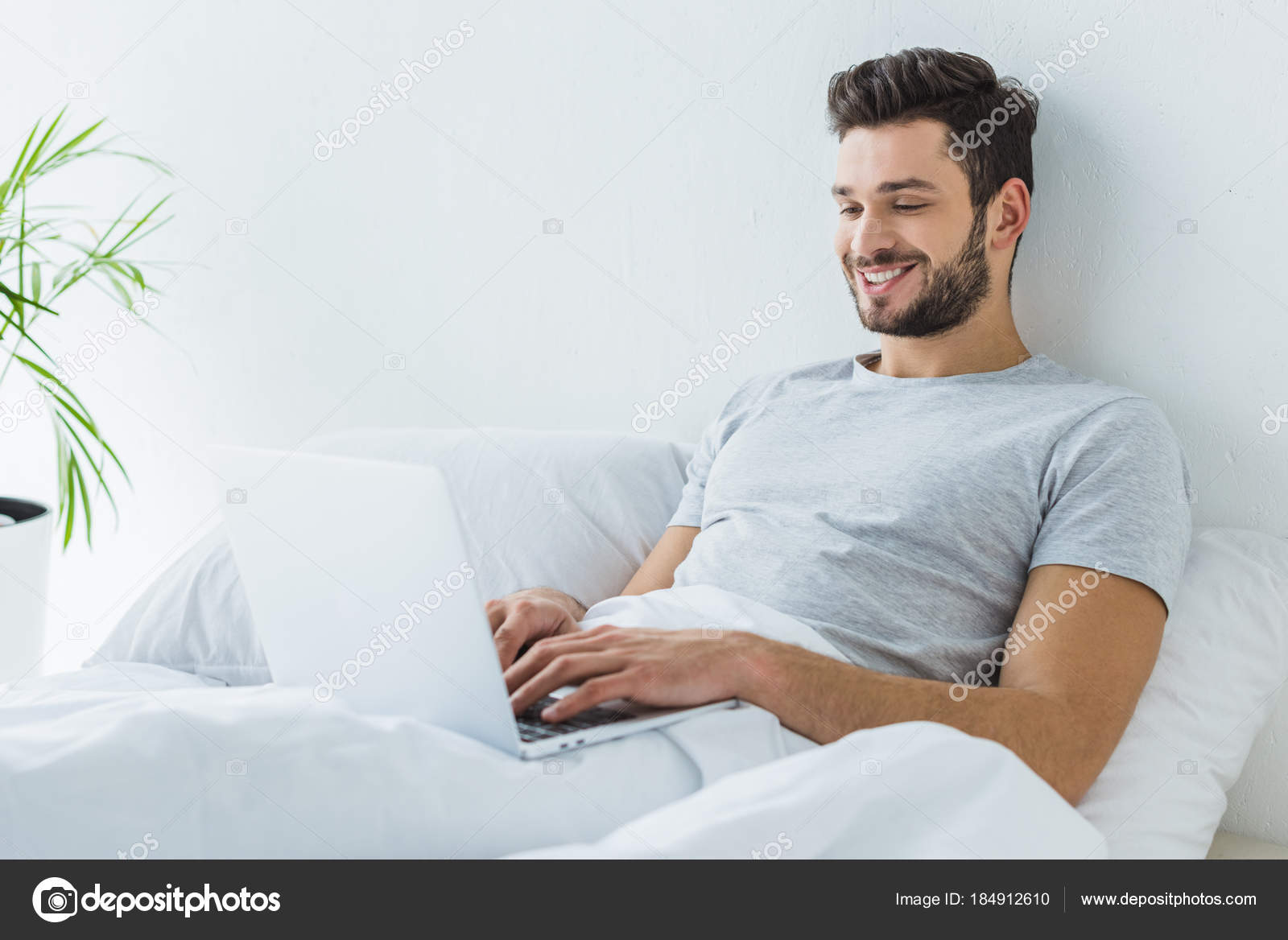Sorrindo Homem Deitado Cama Usando Laptop fotos, imagens de