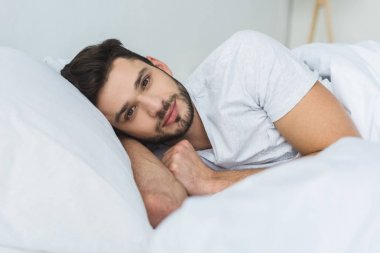 yatakta yatarken ve sabah kameraya bakarak yakışıklı adam