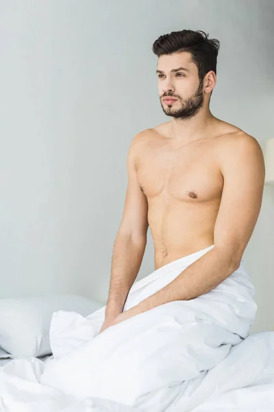 Schöner Bärtiger Mann Ohne Hemd Sitzt Auf Weißem Bett — Stockfoto