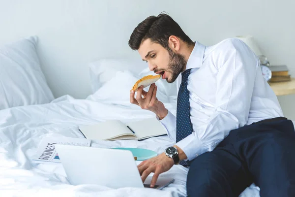 Geschäftsmann Isst Toast Zum Frühstück Während Mit Laptop Bett Arbeitet — Stockfoto