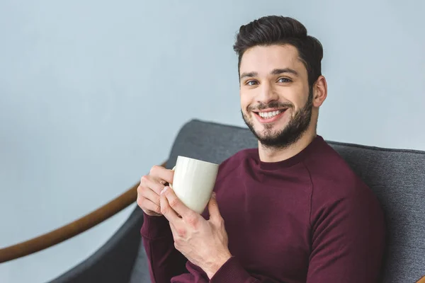 Homem Barbudo Bonito Feliz Segurando Copo Com Bebida Sentado Sofá — Fotografia de Stock