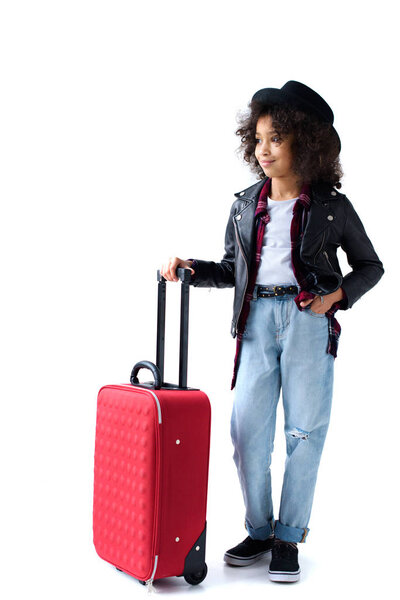 beautiful little child standing with luggage and looking away isolated on white