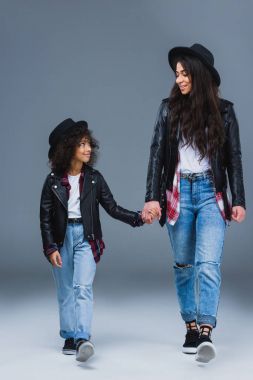 mutlu moda anne ve kızı birlikte yürüyüş ve gri elele