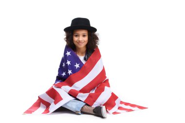 beautiful little child sitting on floor covered in usa flaf isolated on white clipart