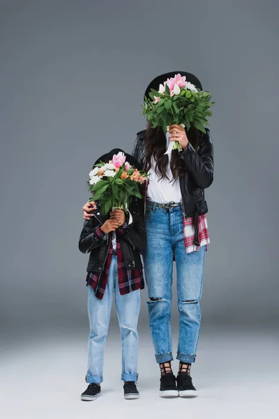 Mère Fille Couvrant Les Visages Bouquets Sur Gris — Photo gratuite