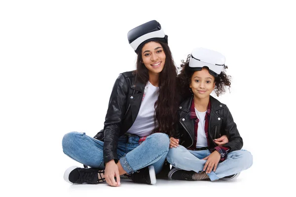 年轻的母亲和女儿在虚拟现实耳机坐在地板上孤立的白色 — 图库照片