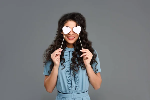 Sorrindo Jovem Mulher Cobrindo Olhos Com Corações Paus Isolados Cinza — Fotografia de Stock