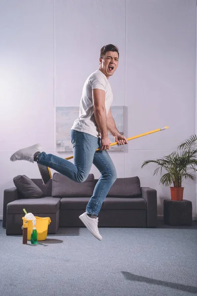 Handsome Man Jumping Broom Living Room — Stock Photo, Image