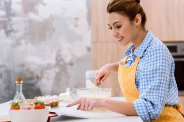 Mutfak yemek yaparken tablet kullanarak çekici genç kadın