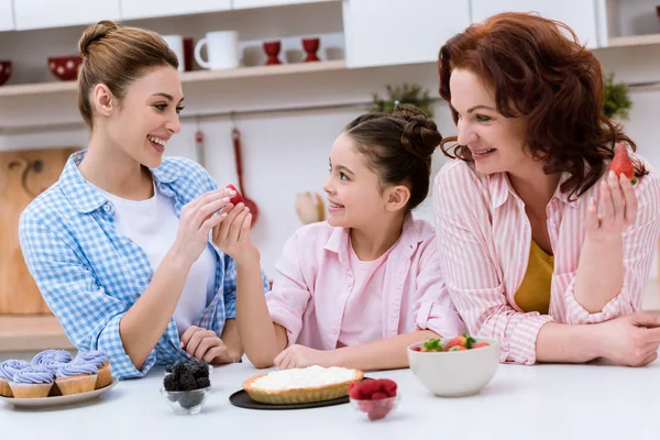Три Поколения Смеющихся Женщин Вместе Украшают Десерт Ягодами Кухне — стоковое фото