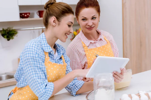 Young Woman Her Mother Using Tablet Together Kitchen While Cooking — Free Stock Photo