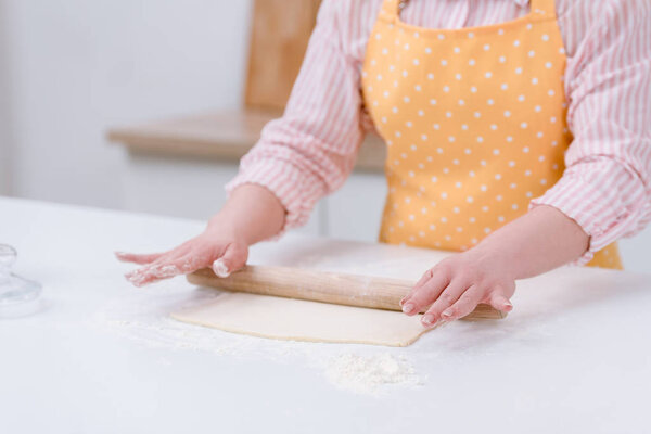 cropped shot of woman rolling dough for pastry at kitchen