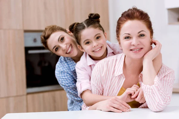三代快乐美丽的妇女站在一起在厨房和看相机 — 图库照片