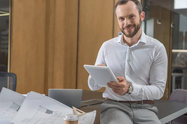 Bonito Arquiteto Feliz Sentado Mesa Com Planos Usando Tablet Escritório — Fotografia de Stock