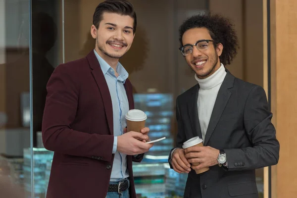 オフィスでのコーヒーの紙コップと幸せの若手ビジネスマン  — 無料ストックフォト