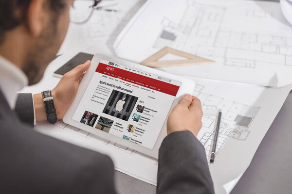 cropped shot of young architect using tablet at workplace with bbc website on screen