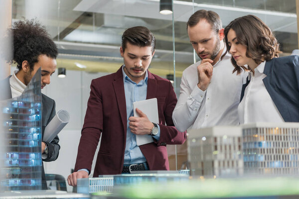 группа вдумчивых архитекторов обсуждают строительные модели в офисе
