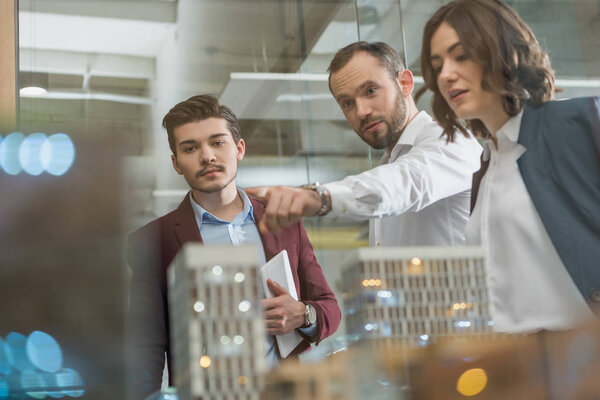 команда успешных архитекторов обсуждает модель миниатюрного города
