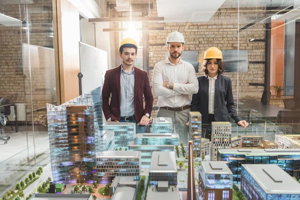 Equipe Arquitetos Chapéus Duros Frente Modelo Cidade Miniatura Escritório — Fotografia de Stock