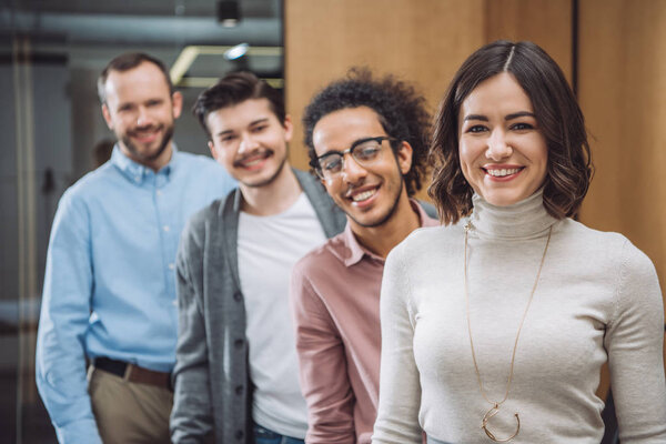 группа успешных бизнесменов, стоящих в ряд и смотрящих в камеру в офисе
