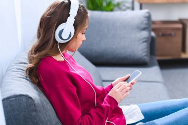 genç kadın Kulaklığımda smartphone kullanarak yan görünüm
