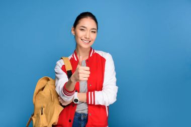 portrait of smiling asian student showing thumb up isolated on blue clipart