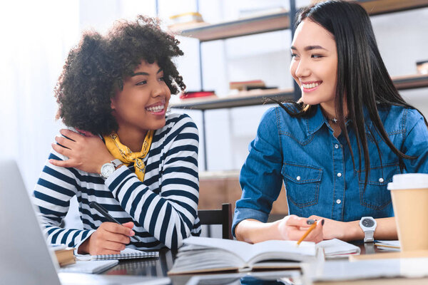 portrait of cheerful multiracial students doing homework together