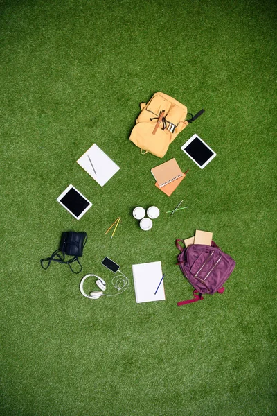 Widok Góry Ułożone Urządzeń Cyfrowych Plecaki Notebooków Zielony Trawnik — Zdjęcie stockowe