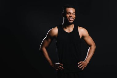 Bel üzerinde gülümseyen kas Afrikalı-Amerikalı adam ile ayakta eller ve seyir uzakta üstünde siyah izole