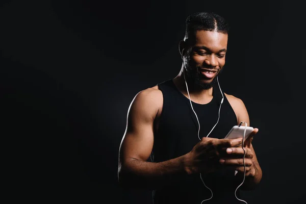 Sonriente Musculoso Afroamericano Hombre Auriculares Usando Teléfono Inteligente Aislado Negro — Foto de Stock