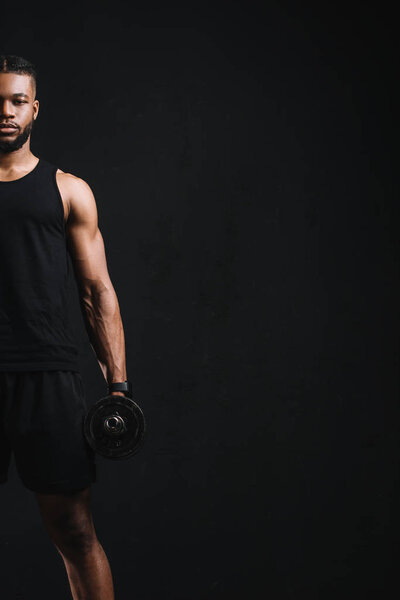 cropped shot of young african american sportsman holding dumbbell isolated on black