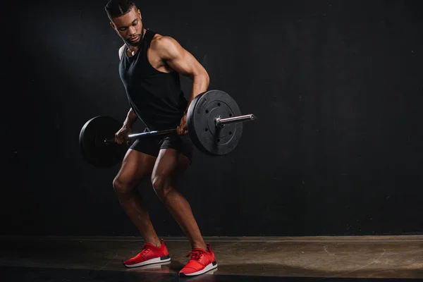 全长视图肌肉年轻的非洲裔美国运动员起重杠铃在黑色 — 图库照片