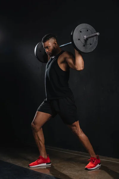 黒のバーベルを持ち上げる筋肉の若いアフリカ系アメリカ人のスポーツマン — ストック写真
