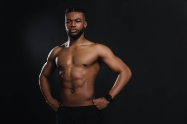 Bel ve siyahta izole kamera bakarak kas genç Afro-Amerikan sporcu ile ayakta eller