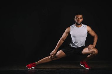 atletik Afro-Amerikan delikanlı egzersiz ve kameraya siyah üzerinde seyir spor giyim