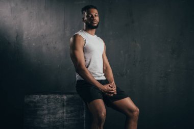 genç atletik Afrikalı-Amerikalı adam oturan ve kameraya siyah üzerinde seyir spor giyim 