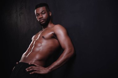 handsome shirtless muscular african american man looking at camera on black  clipart