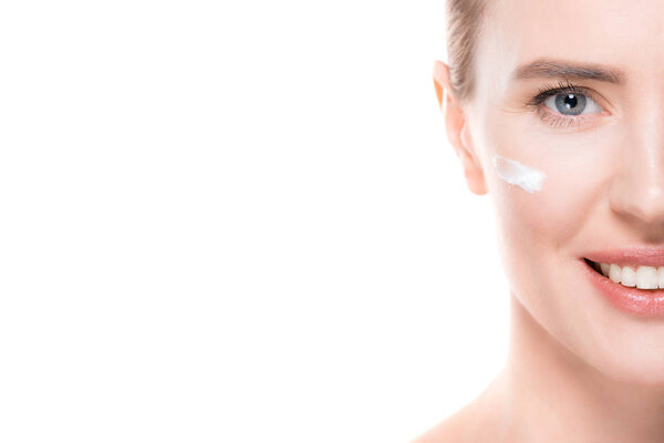 Обрезанный вид женщины с кремом на коже лица изолирован на белом
