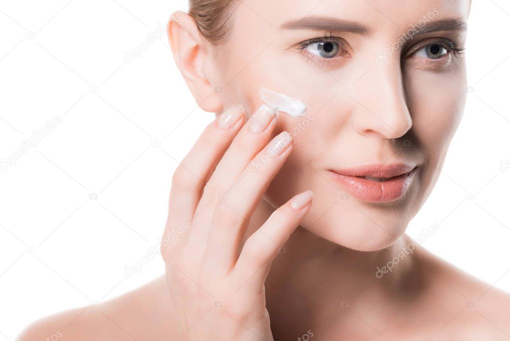 Female applying cream on face isolated on white