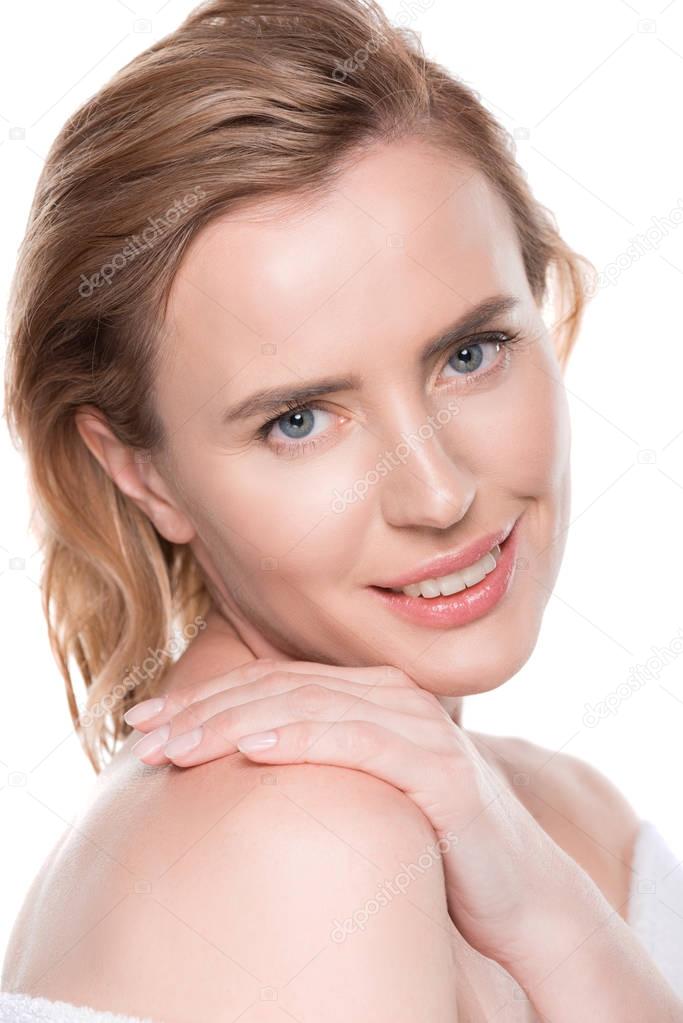 Smiling woman with clean skin touching own shoulder isolated on white