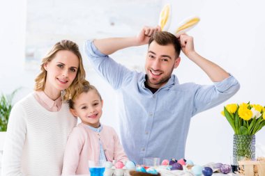 Mutlu aile Paskalya için renkli yumurta ile tabloya göre tavşan kulakları ile oynamak