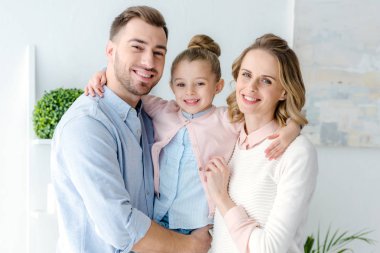 Küçük kızı ile gülümseyen aile kucaklayan 