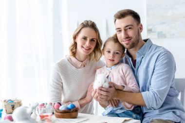 Mutlu aile masada boyalı yumurta paskalya tavşanına holding