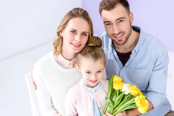 Adorable child and parents holding bouquet of tulips on 8 march