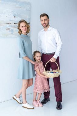 Sevimli çocuk ve ebeveynleri ile renkli yumurta Paskalya sepeti