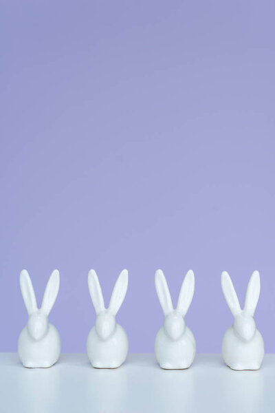 Bunny statuettes in row on violet background