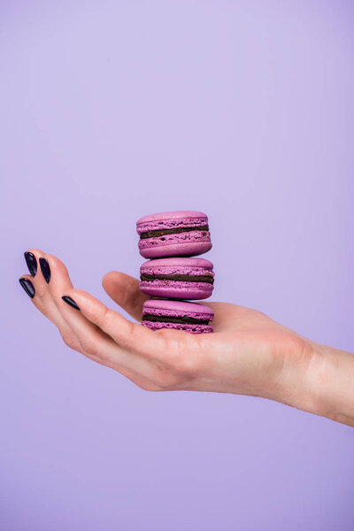 Woman holding macarons isolated on violet
